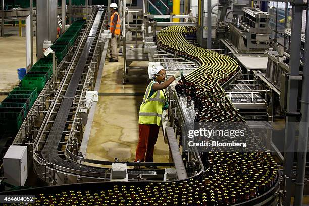 Worker inspects bottles of beer as they move along a conveyor belt on the bottling line at the Meta Abo brewery, operated by Diageo Plc, in Sebeta,...