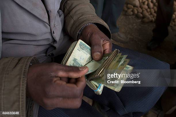 Farmer counts out his cash payment for barley grain in Ethiopian birr banknotes from a buyer for Diageo Plc's Meta Abo brewery in the village of Damo...