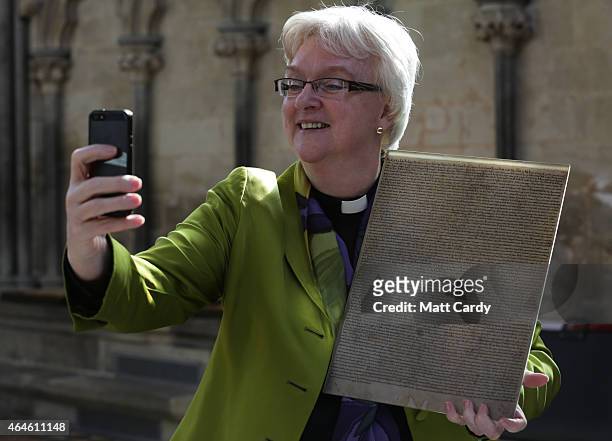 The Very Revd. June Osborne, Dean of Salisbury takes a selfie holding a modern day copy of the Magna Carta in Salisbury Cathedral's Cloisters and...