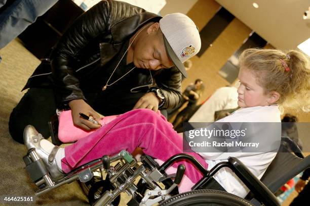 Actor Kyle Massey signs a patients cast while she awaits recieving her new hearing aids at the Starkey Hearing Foundation Mission during GRAMMY Camp...