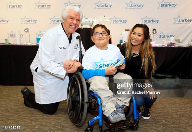 Starkey Founder and CEO William Austin and singer Jessica Sanchez assist patients with fitting new hearing aids at the Starkey Hearing Foundation...