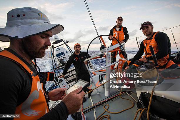 In this handout image provided by the Volvo Ocean Race onboard Team Alvimedica, Charlie Enright reads the 7PM sked aloud to the on-deck watch of Nick...