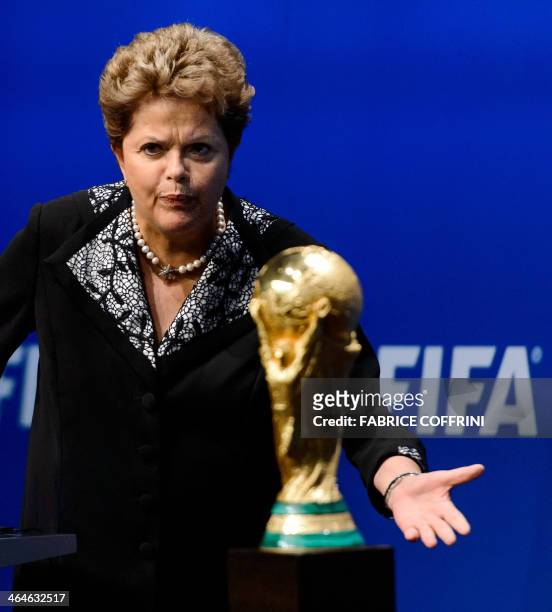 Brazilian President Dilma Rousseff gestures next to the FIFA World Cup trophy during a statement after a meeting with FIFA President Sepp Blatter on...