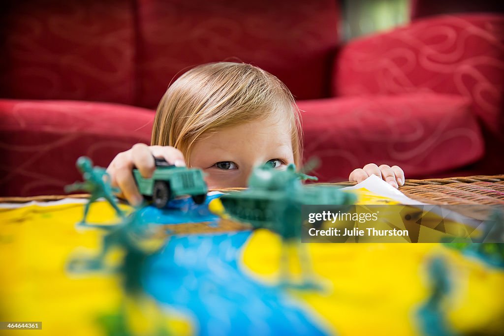 Child Playing with Toy Tanks and Soldiers