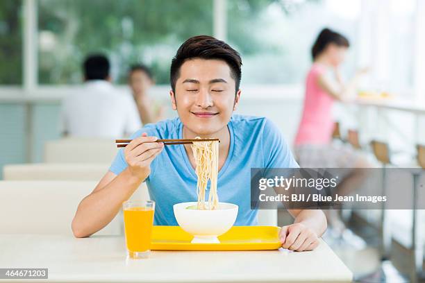 young man enjoying the smell of noodles - noodles eating stock pictures, royalty-free photos & images