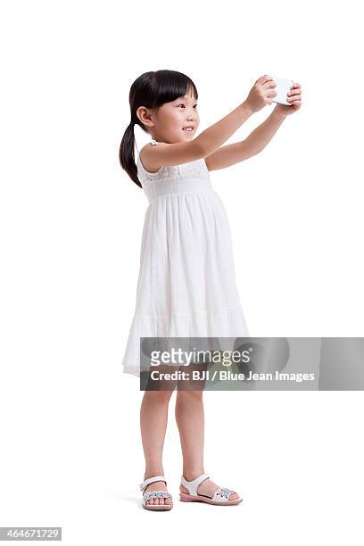 cute little girl taking pictures with smart phone - girl white dress stock pictures, royalty-free photos & images