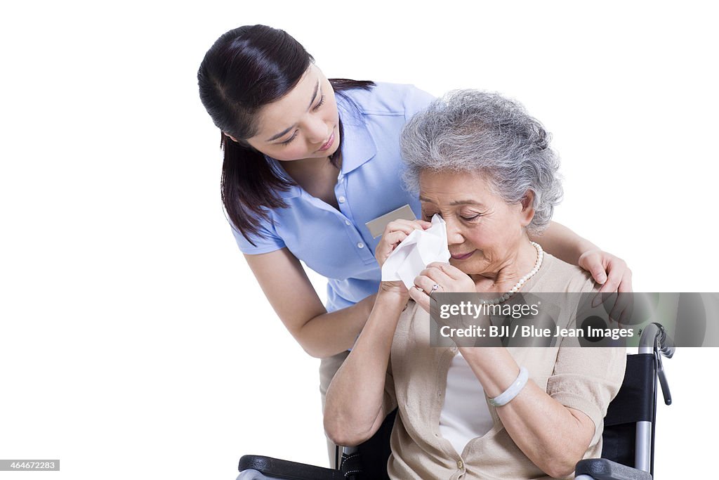 Female nursing worker comforting weeping senior woman