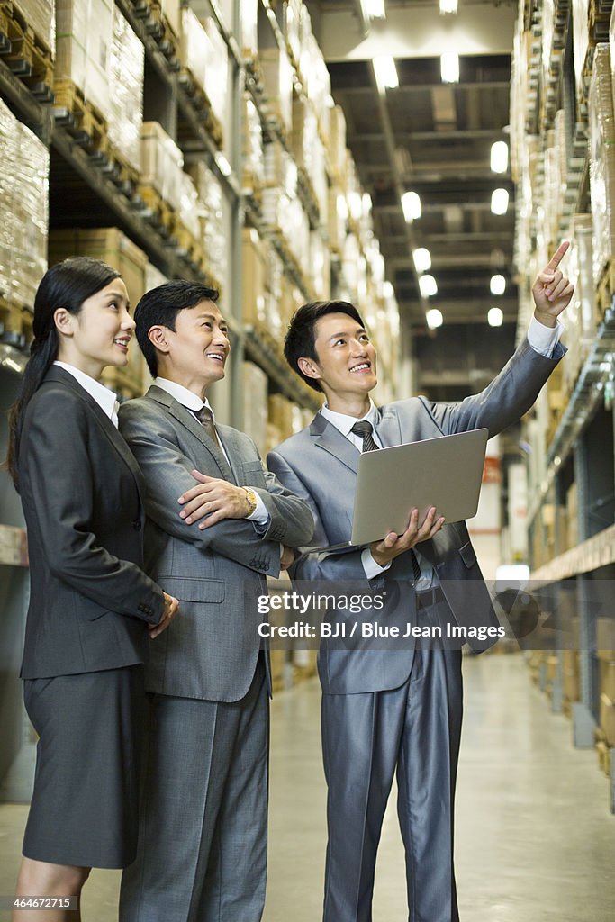 Cheerful business people with laptop in warehouse