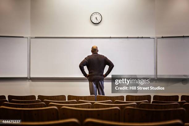 Professor Standing In Empty Classroom, Stock-Foto