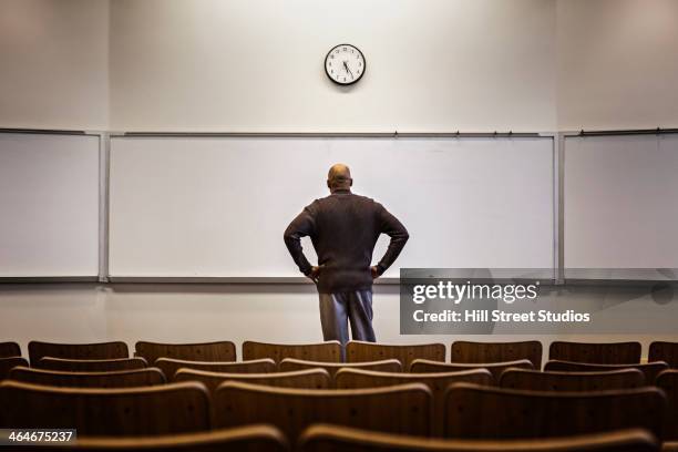 professor standing in empty classroom - schulbeginn stock-fotos und bilder