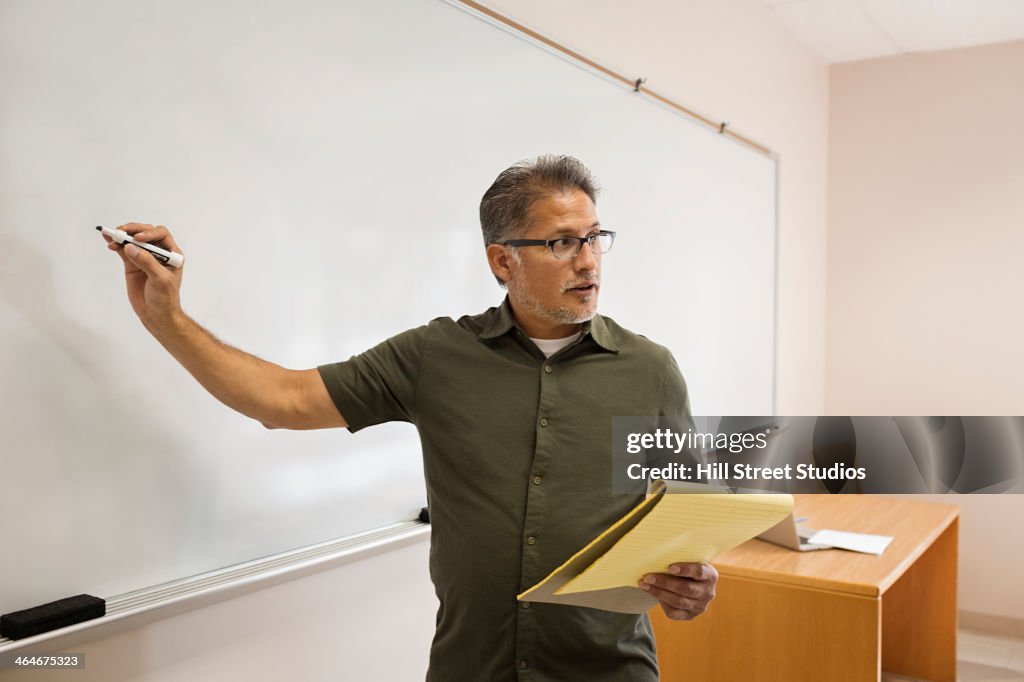 Professor writing on whiteboard in classroom