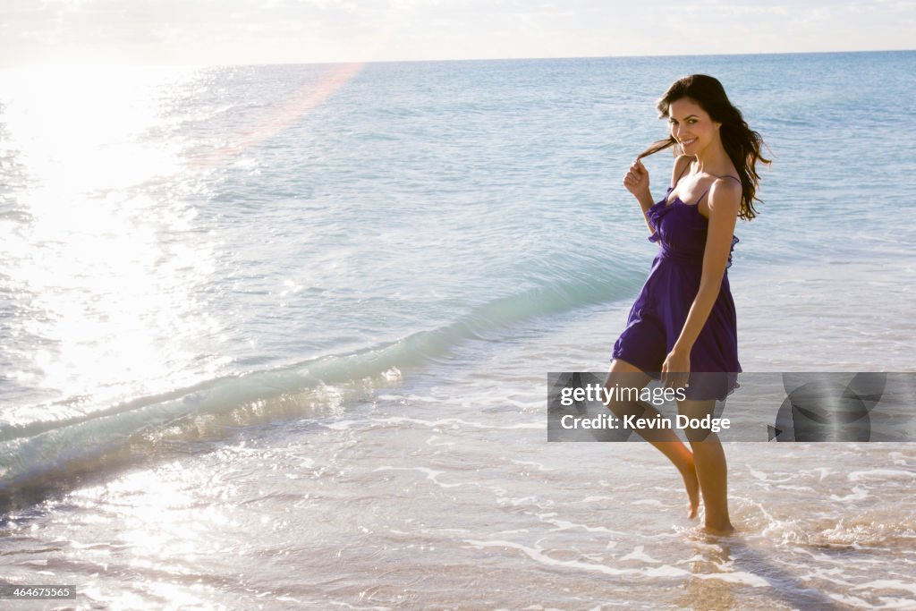 Hispanic woman walking in surf on beach