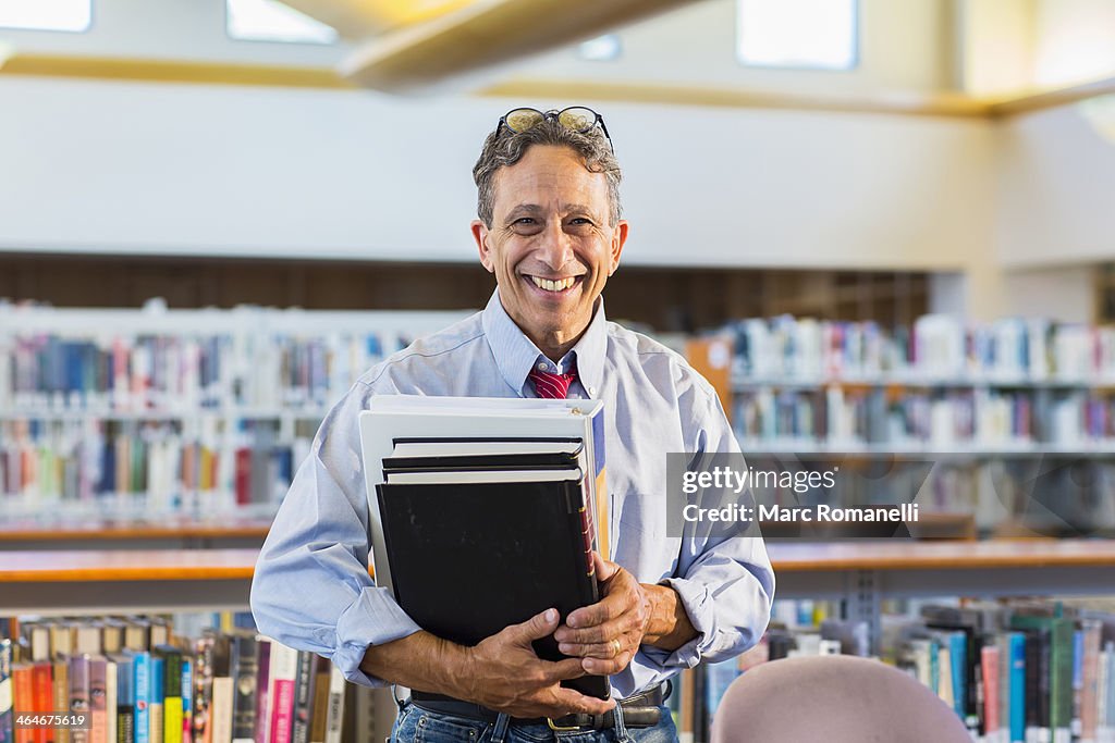 Senior man holding books in library