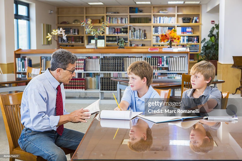 Teacher and students working in library