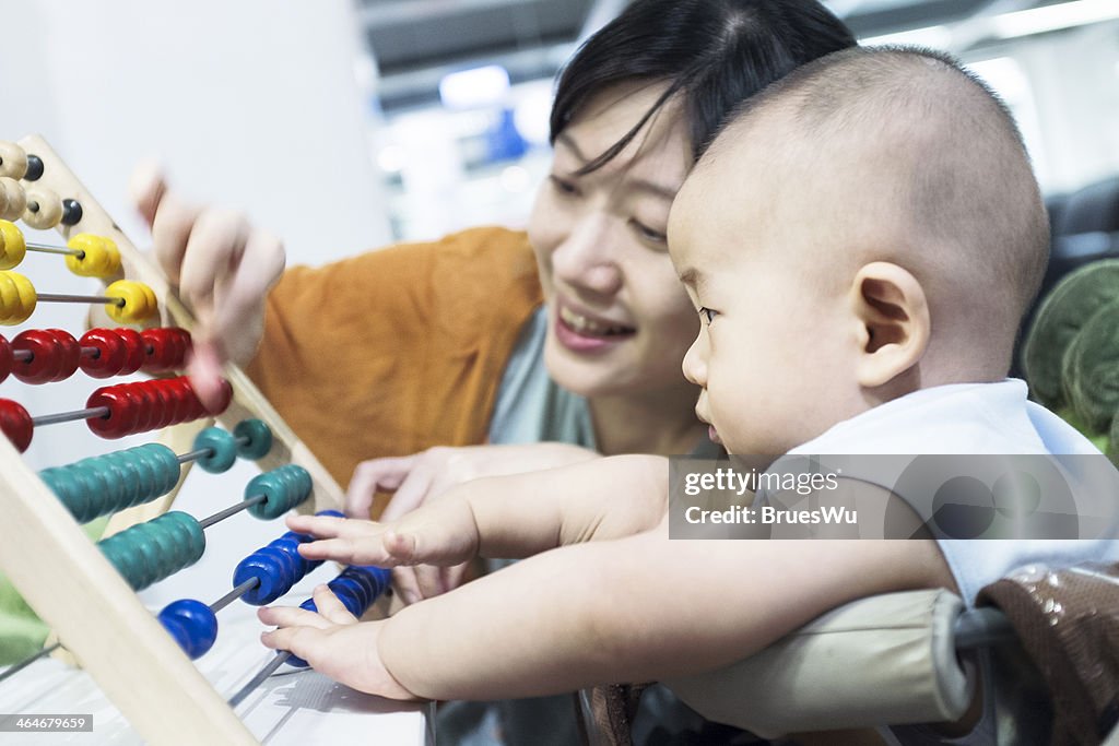 Young mother teaching boy baby with arithmetic toy