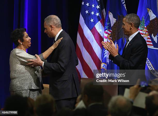 President Barack Obama watches as U.S. Attorney General Eric Holder gets a hug from singer Aretha Franklin after she sang America The Beautiful...