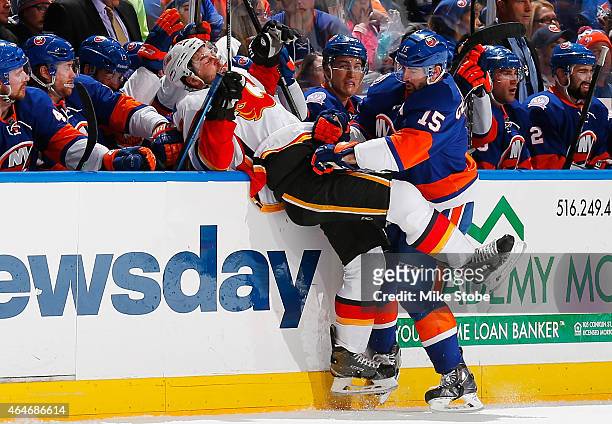 Lance Bouma of the Calgary Flames is checked into the boards by Cal Clutterbuck of the New York Islanders at Nassau Veterans Memorial Coliseum on...