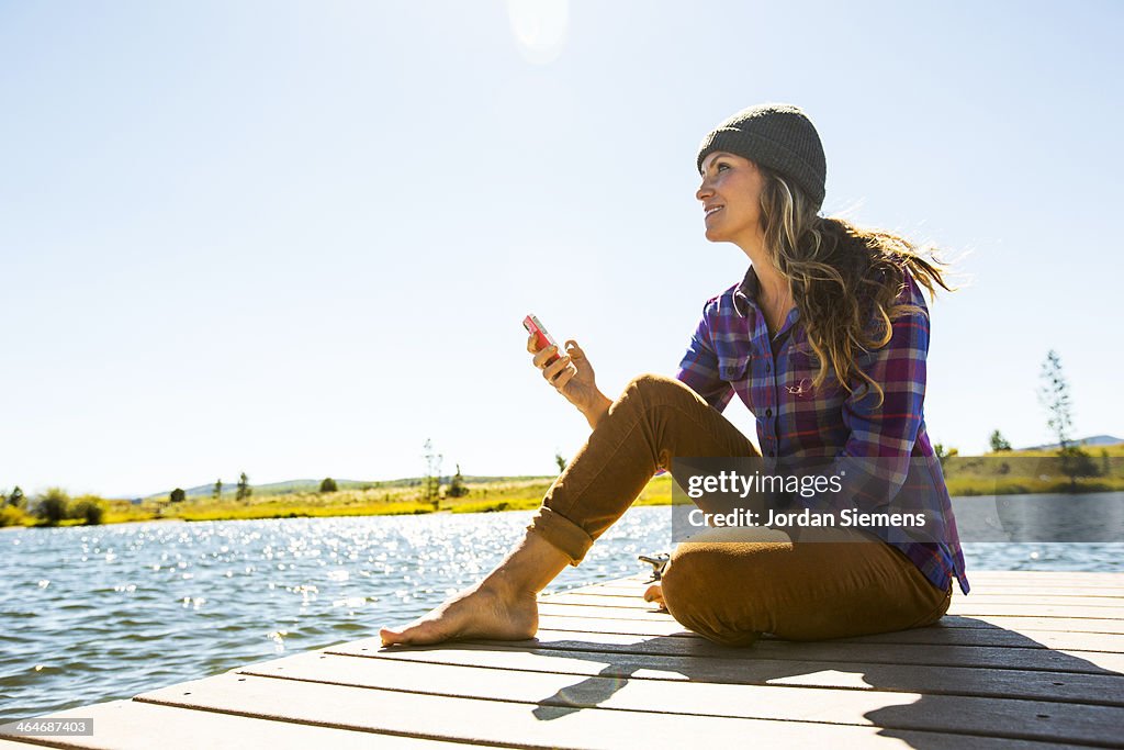 Smiling woman with smart phone on dock
