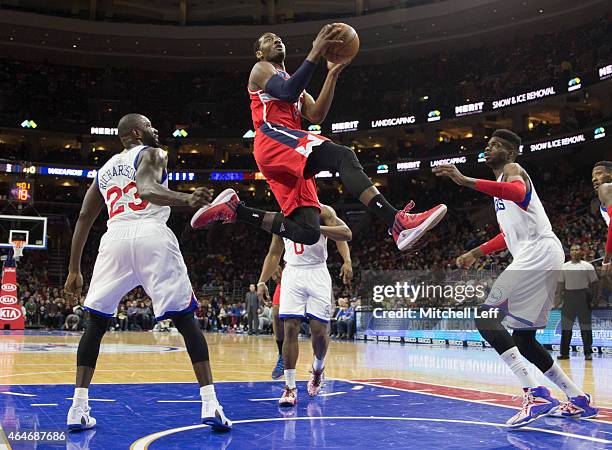 John Wall of the Washington Wizards attempts a layup with Jason Richardson and Nerlens Noel of the Philadelphia 76ers defending on the play on...
