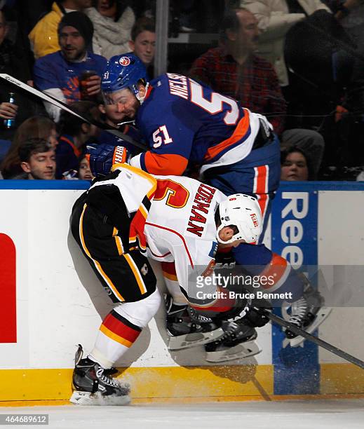 Frans Nielsen of the New York Islanders is checked by Dennis Wideman of the Calgary Flames during the second period at the Nassau Veterans Memorial...