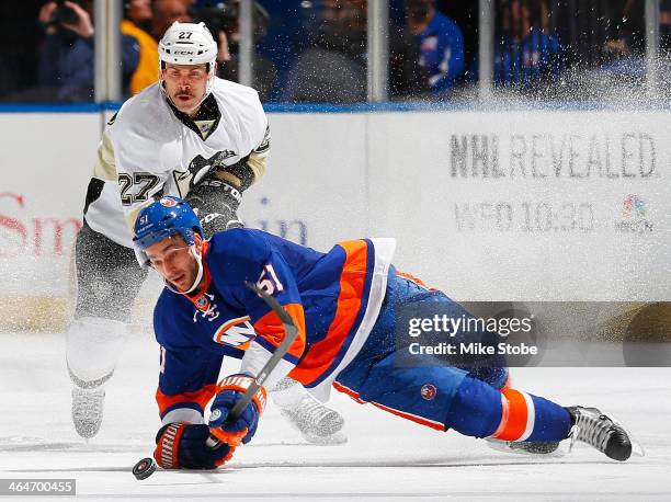 Frans Nielsen of the New York Islanders is tripped up in front of Craig Adams of the Pittsburgh Penguins at Nassau Veterans Memorial Coliseum on...