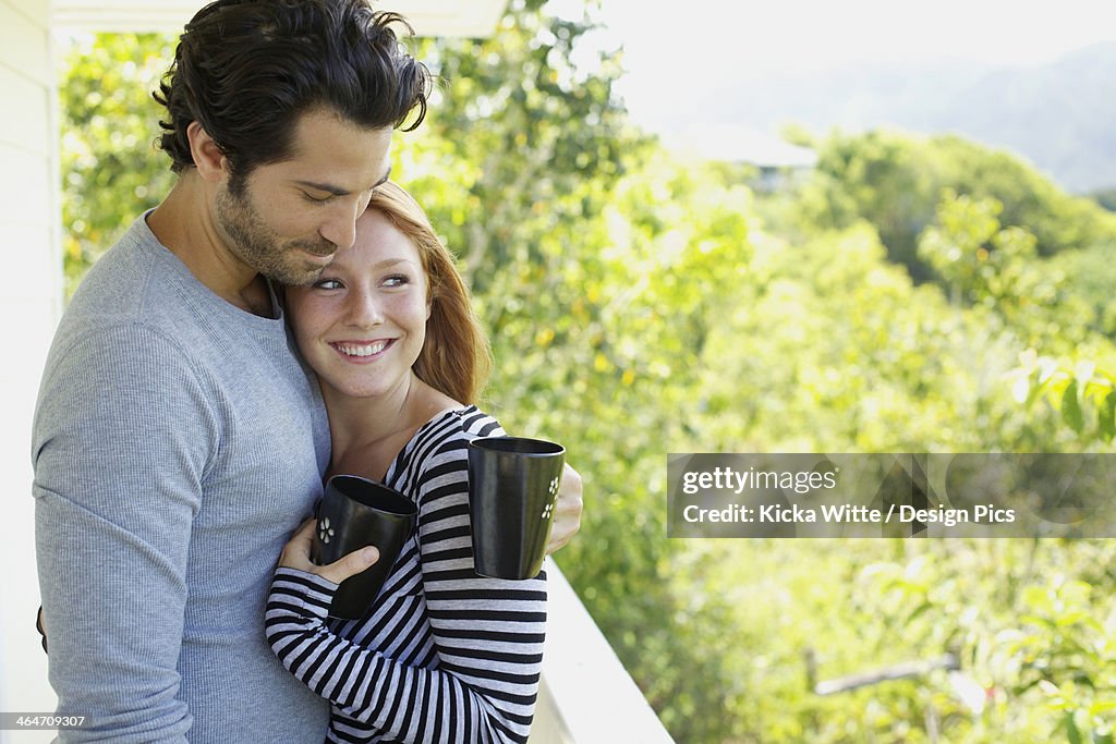 A Couple On A Balcony With Their Coffee Mugs