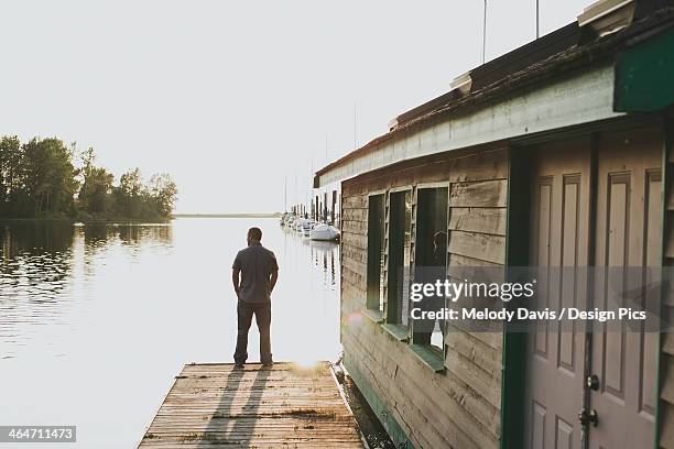 a man standing on the edge of a dock looking out over the ocean - white rock columbia britannica foto e immagini stock