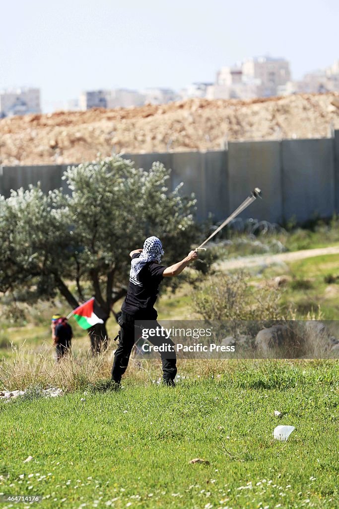 A masked Palestinian youth uses a home-made slingshot to...