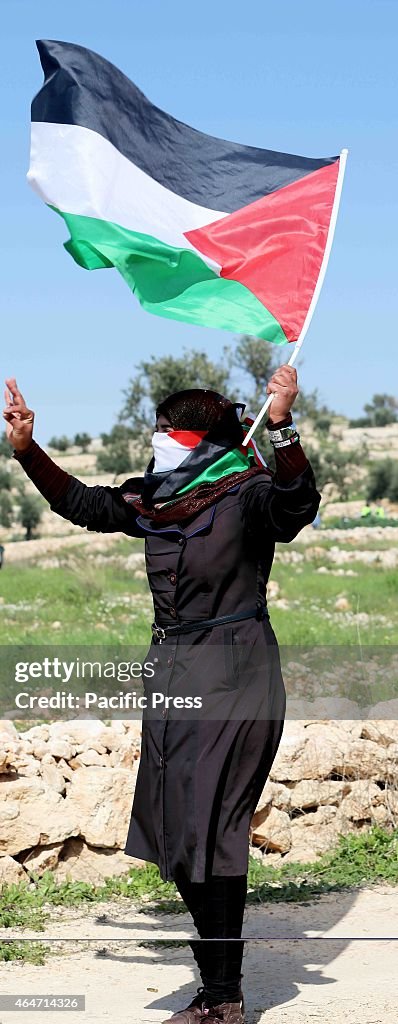 A young Palestinian woman gestures towards Israeli soldiers...