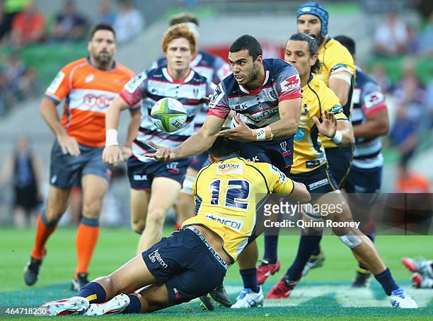 Jack Debreczeni of the Rebels passes the ball whilst being tackled by Christian Lealiifano of the Brumbies during the round three Super Rugby match...