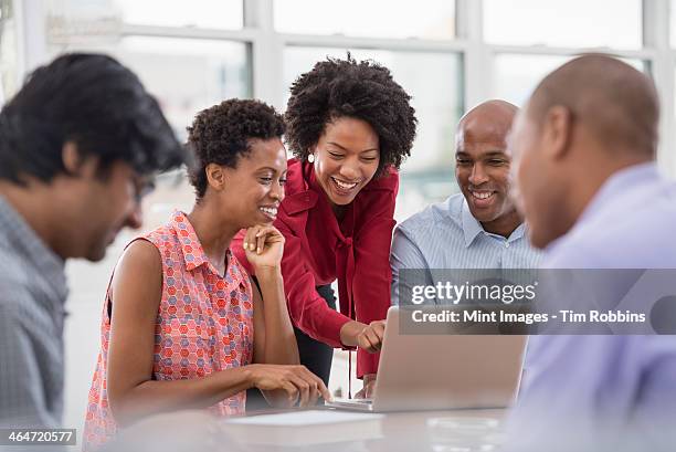 a business environment. a group of people, men and women at a meeting, using a laptop. - indian woman short hair stock pictures, royalty-free photos & images