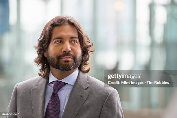 business people out and about in the city. a latino man in a suit jacket and purple tie. - purple suit stock pictures, royalty-free photos & images