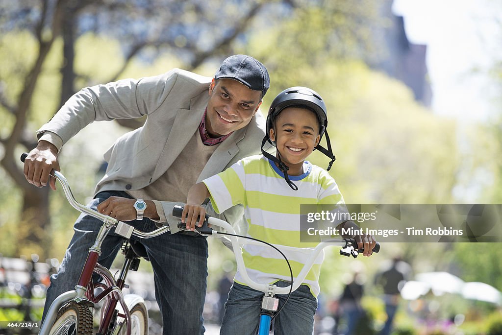 A family in the park on a sunny day. Bicycling and having fun. A father and son side by side.