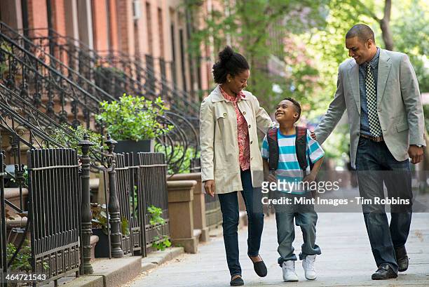 a family outdoors in the city. two parents and a young boy walking together. - 7 steps stockfoto's en -beelden