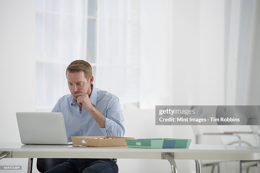 An office in the city. Business. A man sitting at a desk using a laptop.