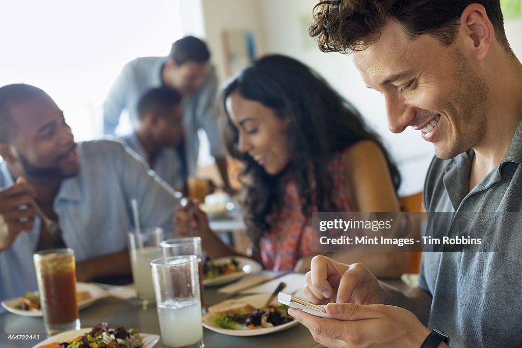 A group of men and women in a cafe,having drinks and enjoying each other's company.