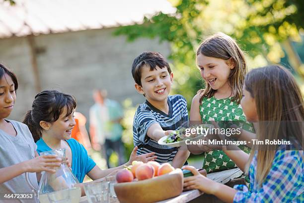 a group of children around a table,eating fresh fruits and salads. - somente crianças imagens e fotografias de stock