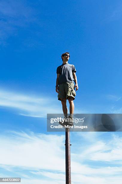man standing and balancing on a metal post,looking towards expansive sky,surprise mountain,alpine lakes wilderness,mt. baker-snoqualmie national forest. - wildnisgebiets name stock-fotos und bilder