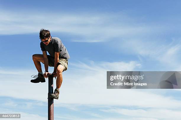 man climbing on to the top of a metal post,on surprise mountain,alpine lakes wilderness,mount baker-snoqualmie national forest. - wildnisgebiets name stock-fotos und bilder