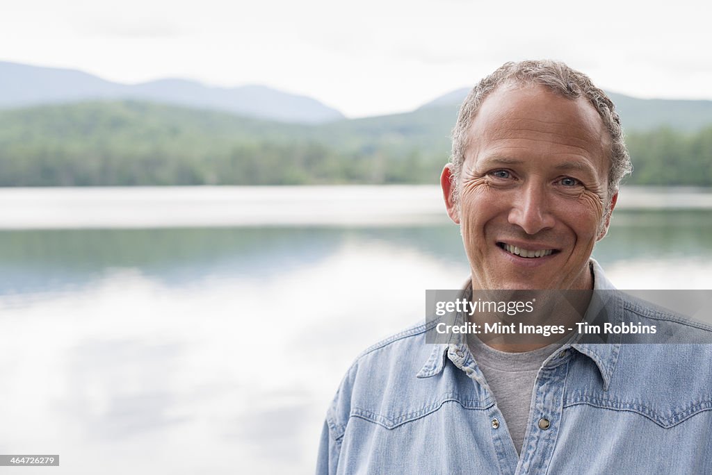 A man on the shore of a lake in New York state.