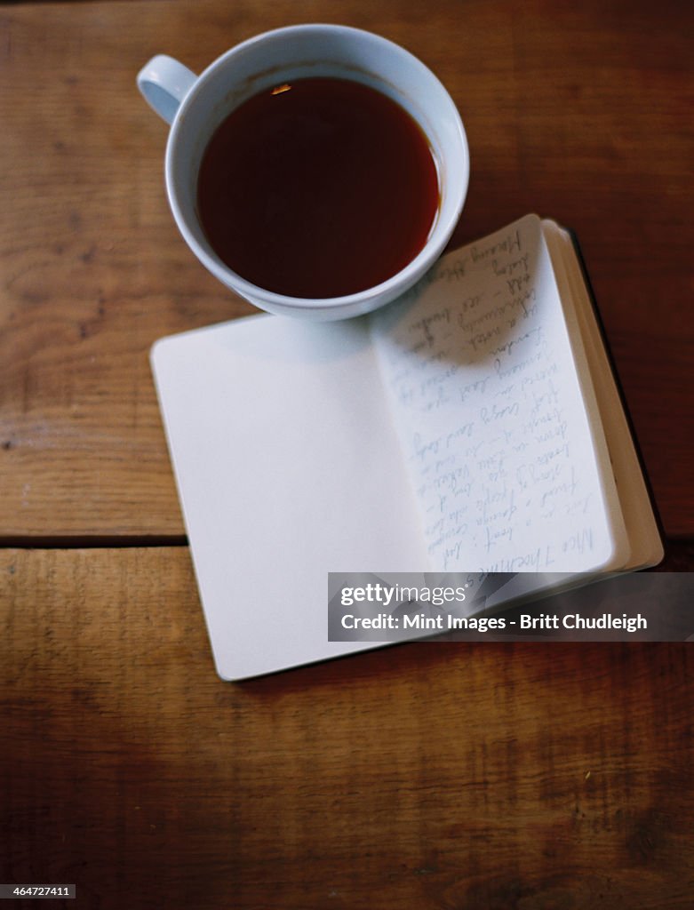 A cold cup of coffee and a handwritten journal.