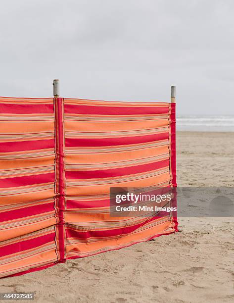 a red striped windbreak on cannon beach on the oregon coast. - beach shelter stockfoto's en -beelden