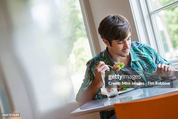 a young man using a digital tablet. - regarder vers le bas photos et images de collection