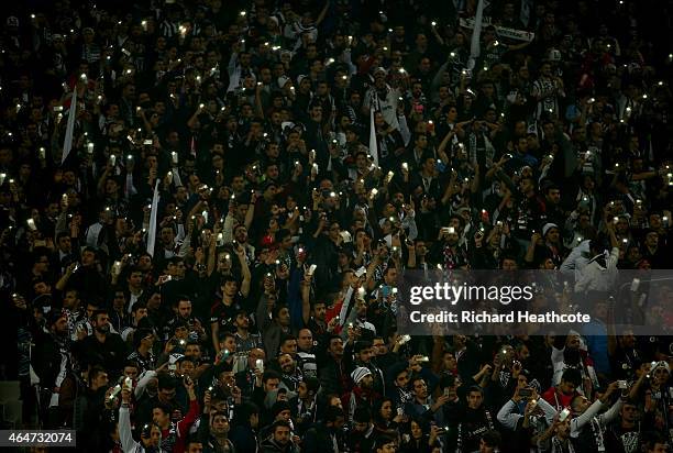 Besiktas fans hold up the lights from their phones during the 2nd leg of the UEFA Europa League Round of 32 match between Besiktas and Liverpool at...