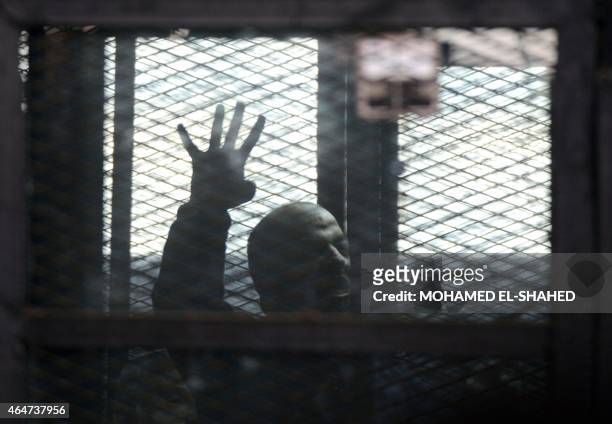 Egyptian Muslim Brotherhood's Mohamed el-Beltagi gestures from the defendants cage during his trial at the non-commissioned police officers institute...