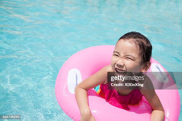 portrait of a cute little girl swimming in the pool with a pink tube - tube girl stock-fotos und bilder