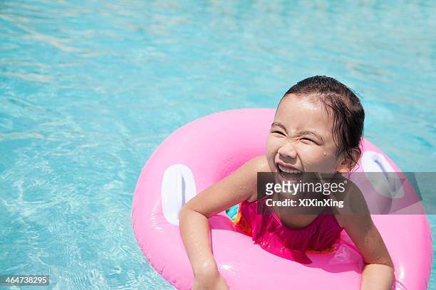 portrait of a cute little girl swimming in the pool with a pink tube - tube girl fotografías e imágenes de stock