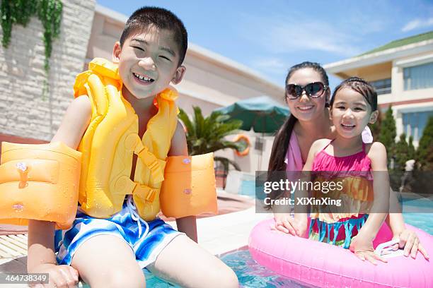 family portrait, mother, daughter, and son, by the pool with pool toys - brazaletes acuáticos fotografías e imágenes de stock