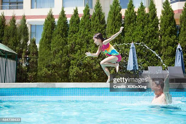 father throwing daughter into the pool, mid-air - young girl jumping into swimming pool stock pictures, royalty-free photos & images