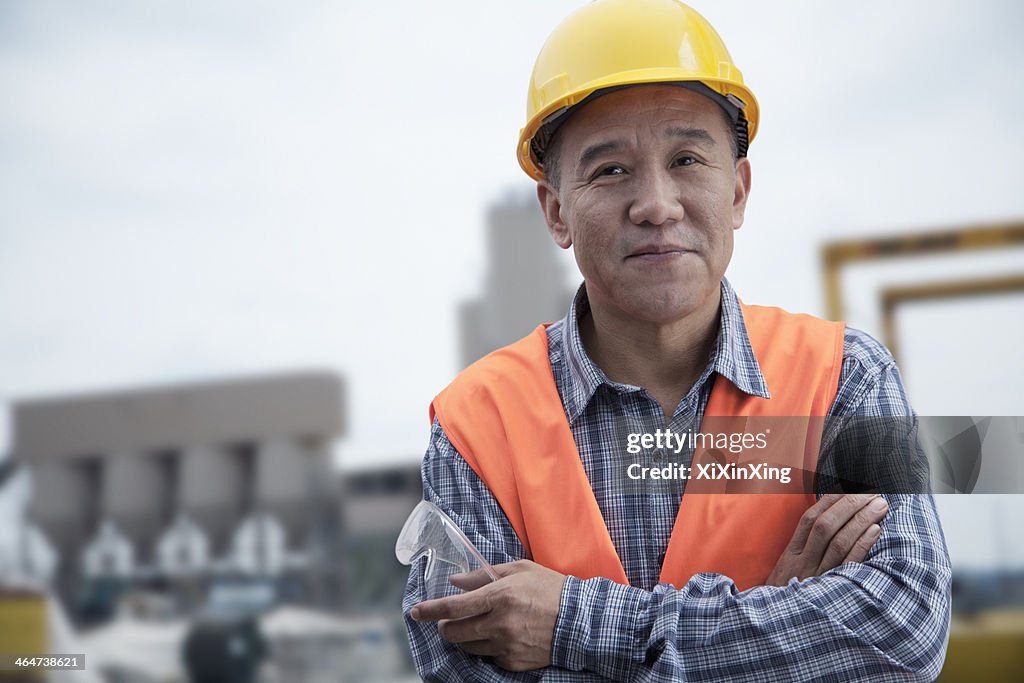 Portrait of proud worker with arms crossed in protective workwear outside of a factory